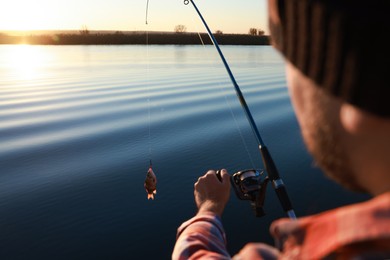 Photo of Fisherman catching fish with rod at riverside, closeup