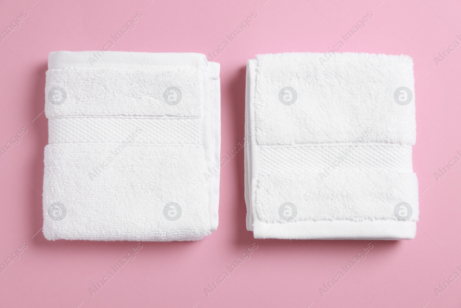 Photo of Soft folded white towels on violet background, flat lay