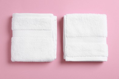 Photo of Soft folded white towels on violet background, flat lay