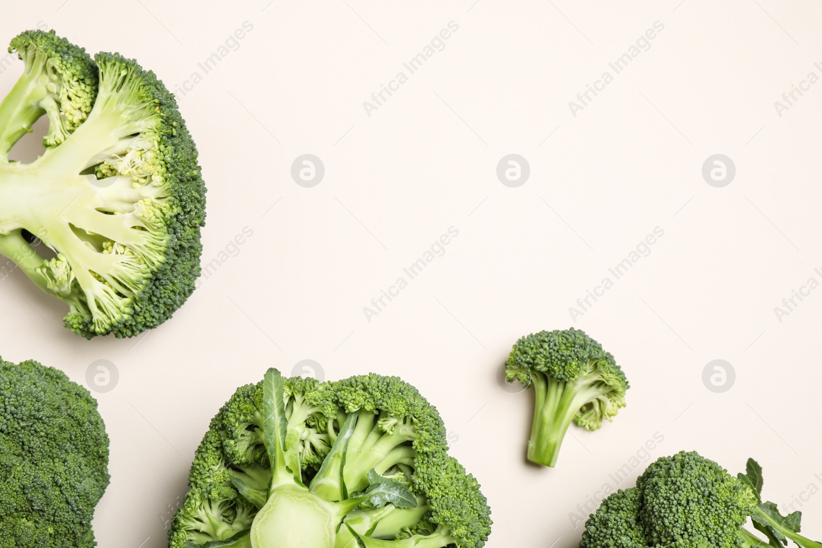 Photo of Fresh tasty broccoli on light beige background, flat lay. Space for text