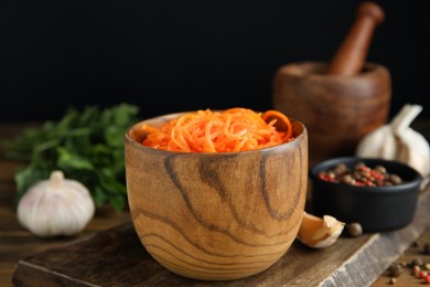 Photo of Delicious Korean carrot salad in bowl on wooden table