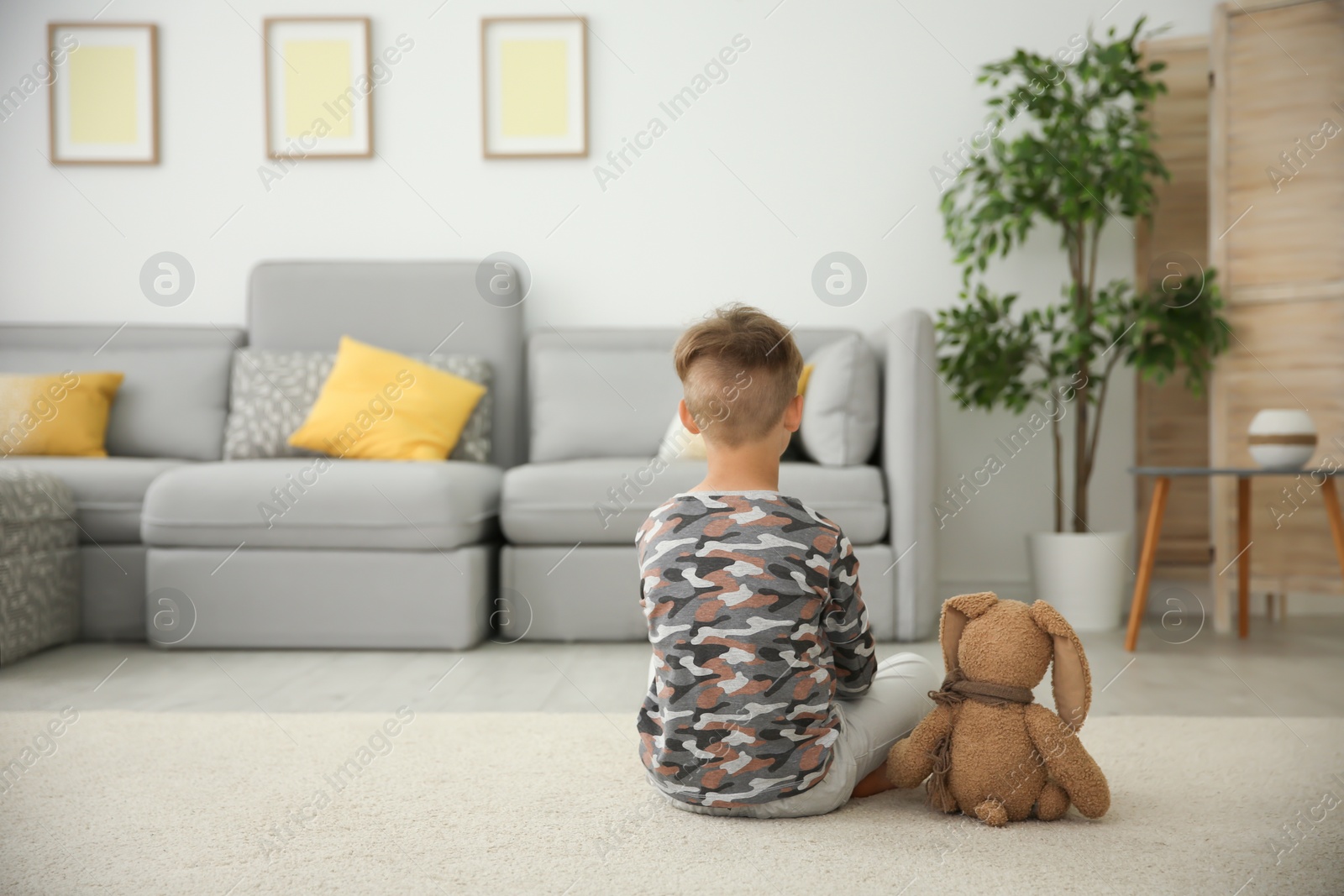 Photo of Little boy with toy sitting on floor in living room. Autism concept