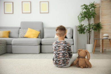 Photo of Little boy with toy sitting on floor in living room. Autism concept