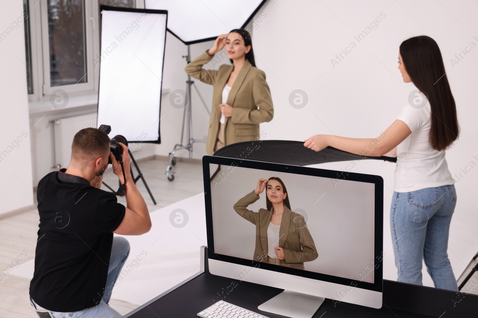 Photo of Professional photographer and assistant working with beautiful model in modern photo studio, selective focus