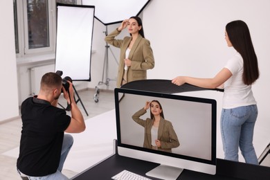Photo of Professional photographer and assistant working with beautiful model in modern photo studio, selective focus