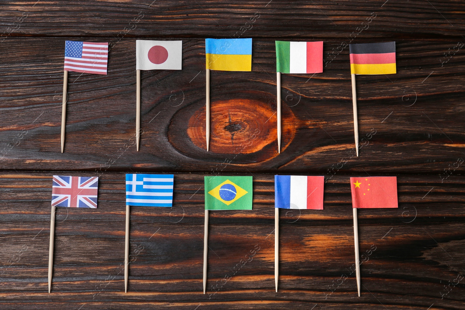 Photo of Many small paper flags of different countries on wooden table, flat lay