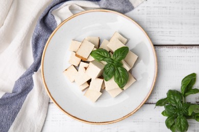 Photo of Plate with delicious smoked tofu and basil on white wooden table, top view