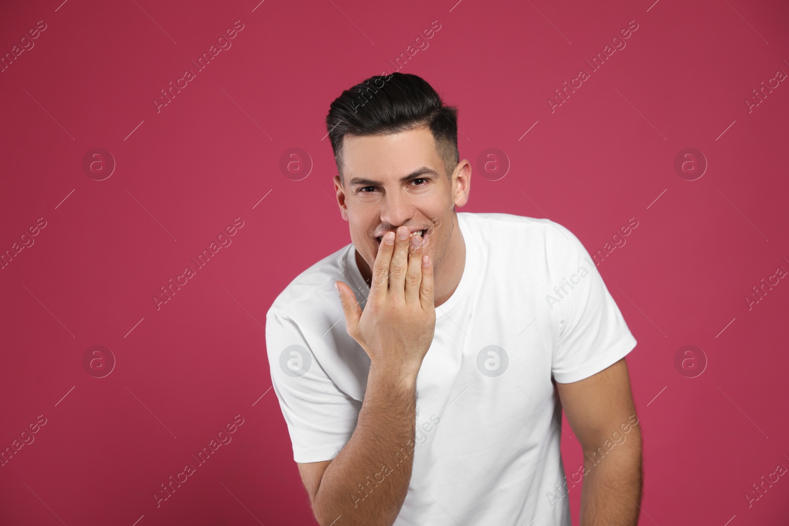 Photo of Handsome man laughing on maroon background. Funny joke