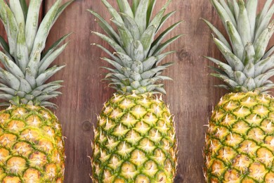 Photo of Delicious ripe pineapples on wooden table, flat lay