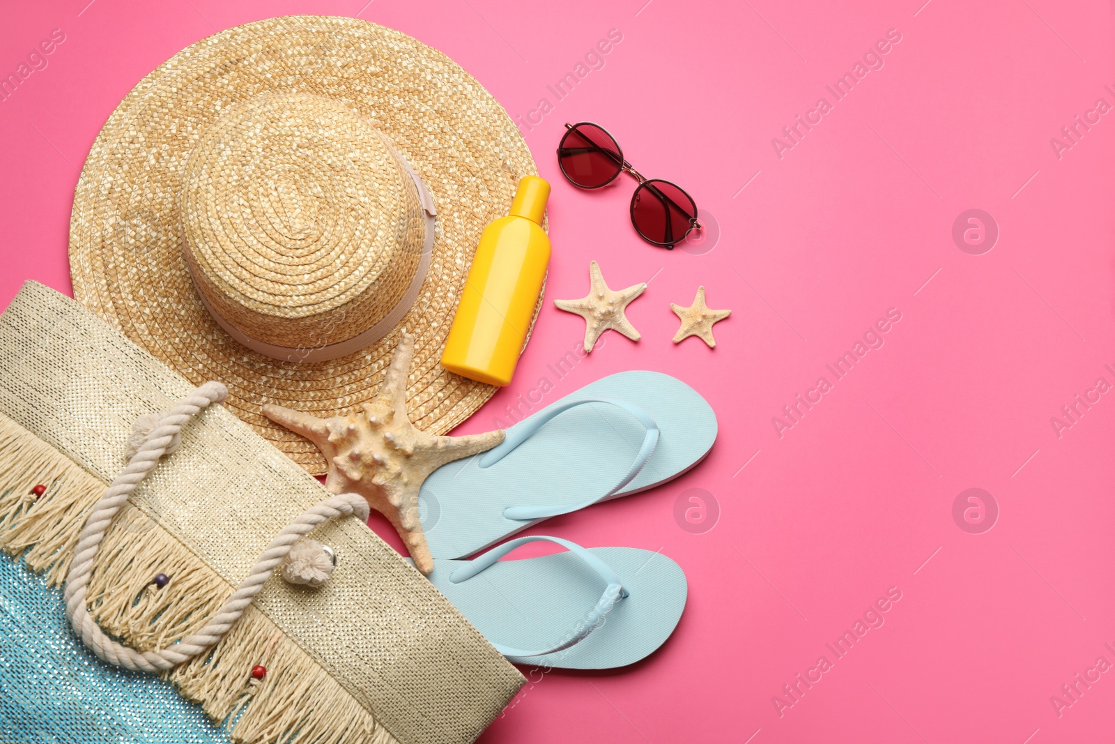 Photo of Stylish bag with beach accessories on pink background, flat lay. Space for text