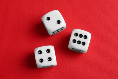 Photo of Three white game dices on red background, flat lay