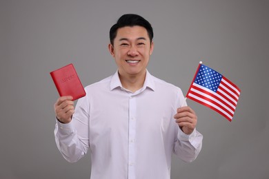 Immigration. Happy man with passport and American flag on grey background