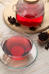 Fresh hibiscus tea and dry flower leaves on wooden table