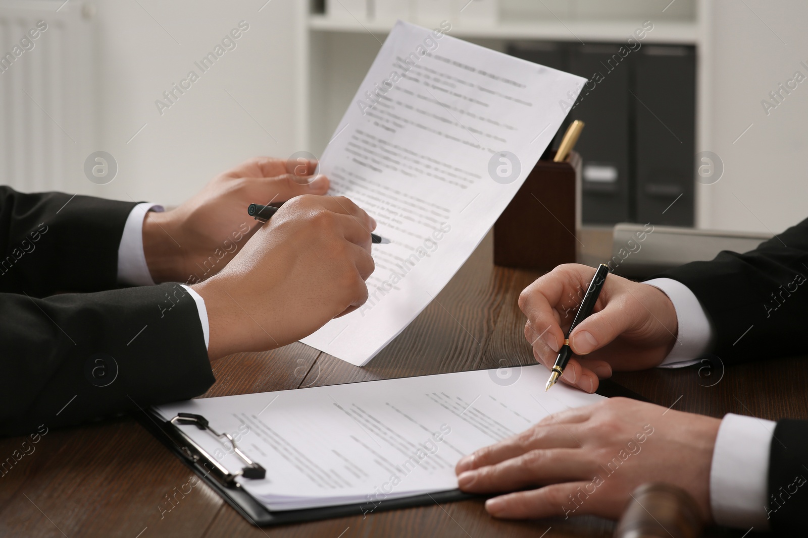 Photo of Law and justice. Lawyers working with documents at wooden table in office, closeup