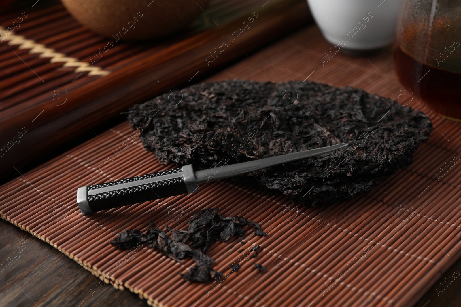 Photo of Broken disc shaped pu-erh tea and knife on wooden table