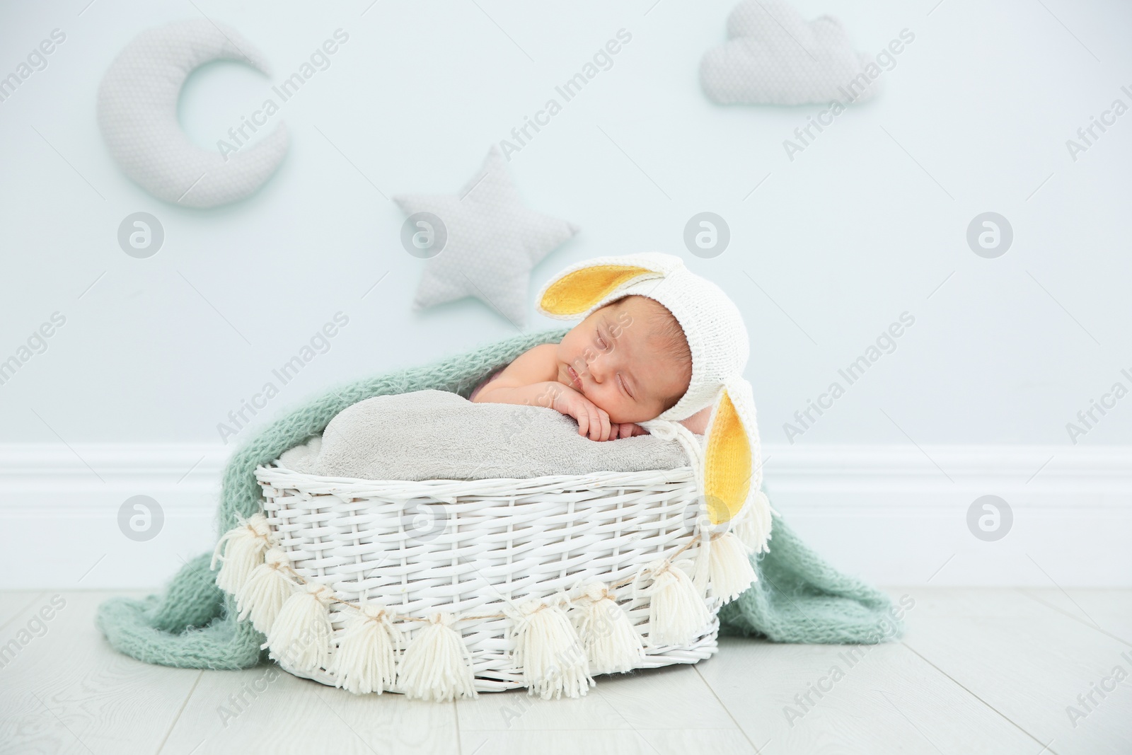 Photo of Adorable newborn child wearing bunny ears hat in baby nest indoors