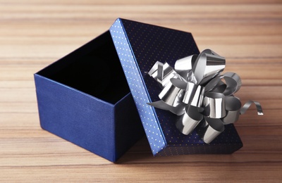 Open empty gift box with bow on wooden table