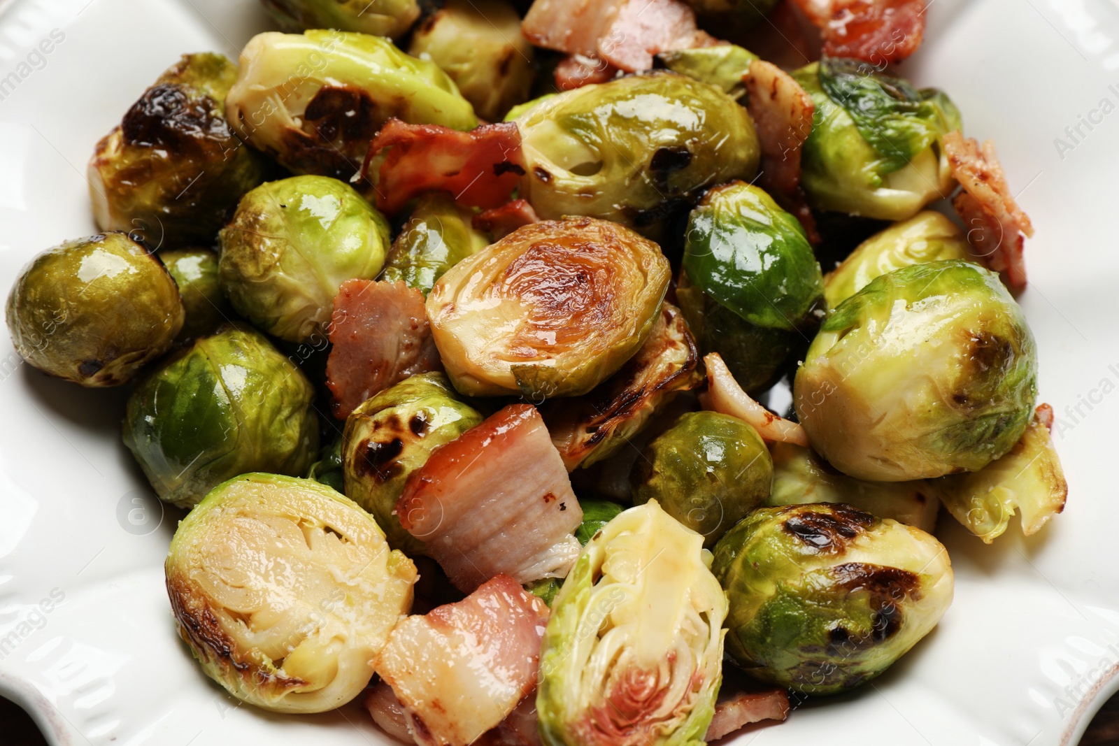 Photo of Delicious Brussels sprouts with bacon in plate, closeup