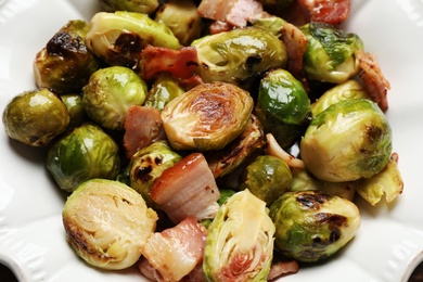 Photo of Delicious Brussels sprouts with bacon in plate, closeup