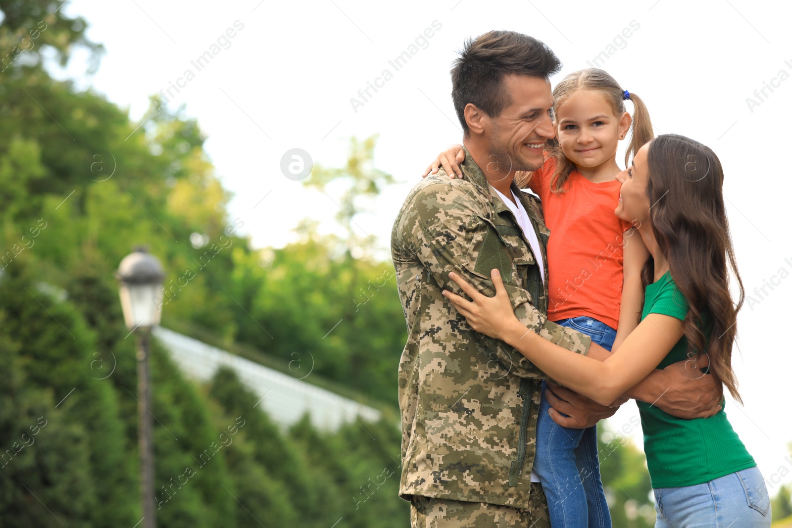 Photo of Man in military uniform with his family  at sunny park