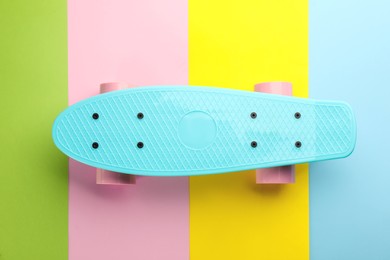 Photo of Turquoise skateboard on color background, top view