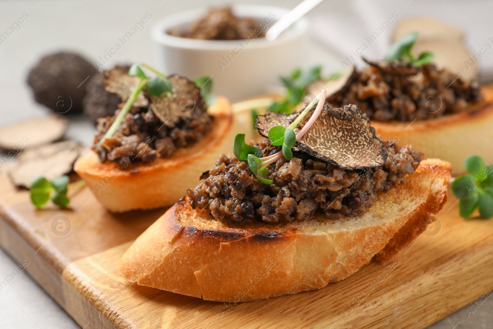 Photo of Tasty bruschettas with truffle paste on wooden board, closeup