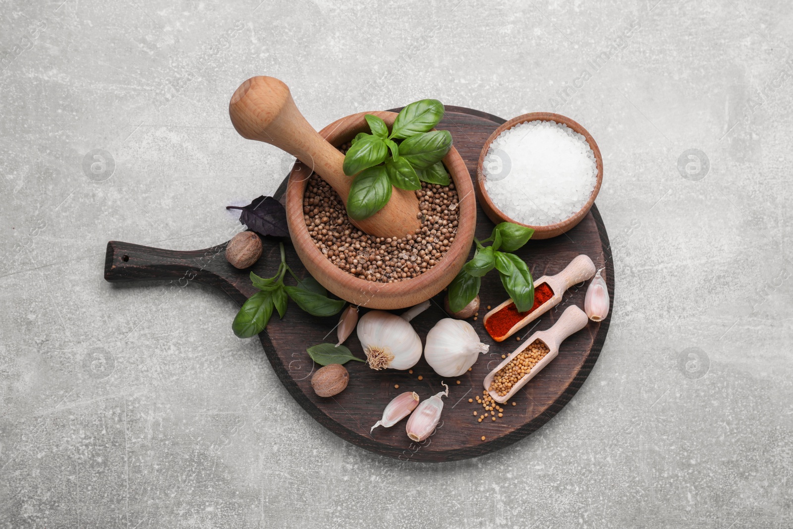 Photo of Mortar with pestle and different spices on light grey table, above view