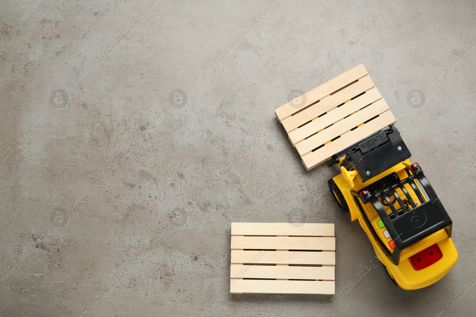 Photo of Toy forklift and wooden pallets on light grey table, flat lay. Space for text