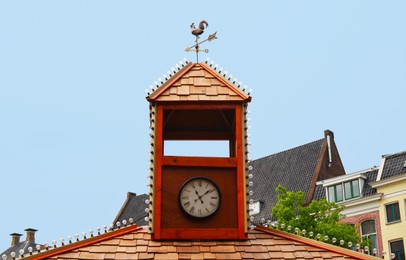 Photo of Tower with clock and weather vane on roof of old building