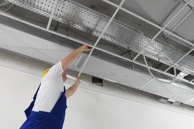 Photo of Worker installing metal frame indoors. Suspended ceiling