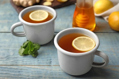 Photo of Cups of hot lemon tea as cough remedy on wooden table