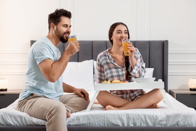 Photo of Happy couple having breakfast on bed at home