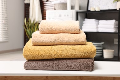 Photo of Stack of clean towels on white table in laundry room
