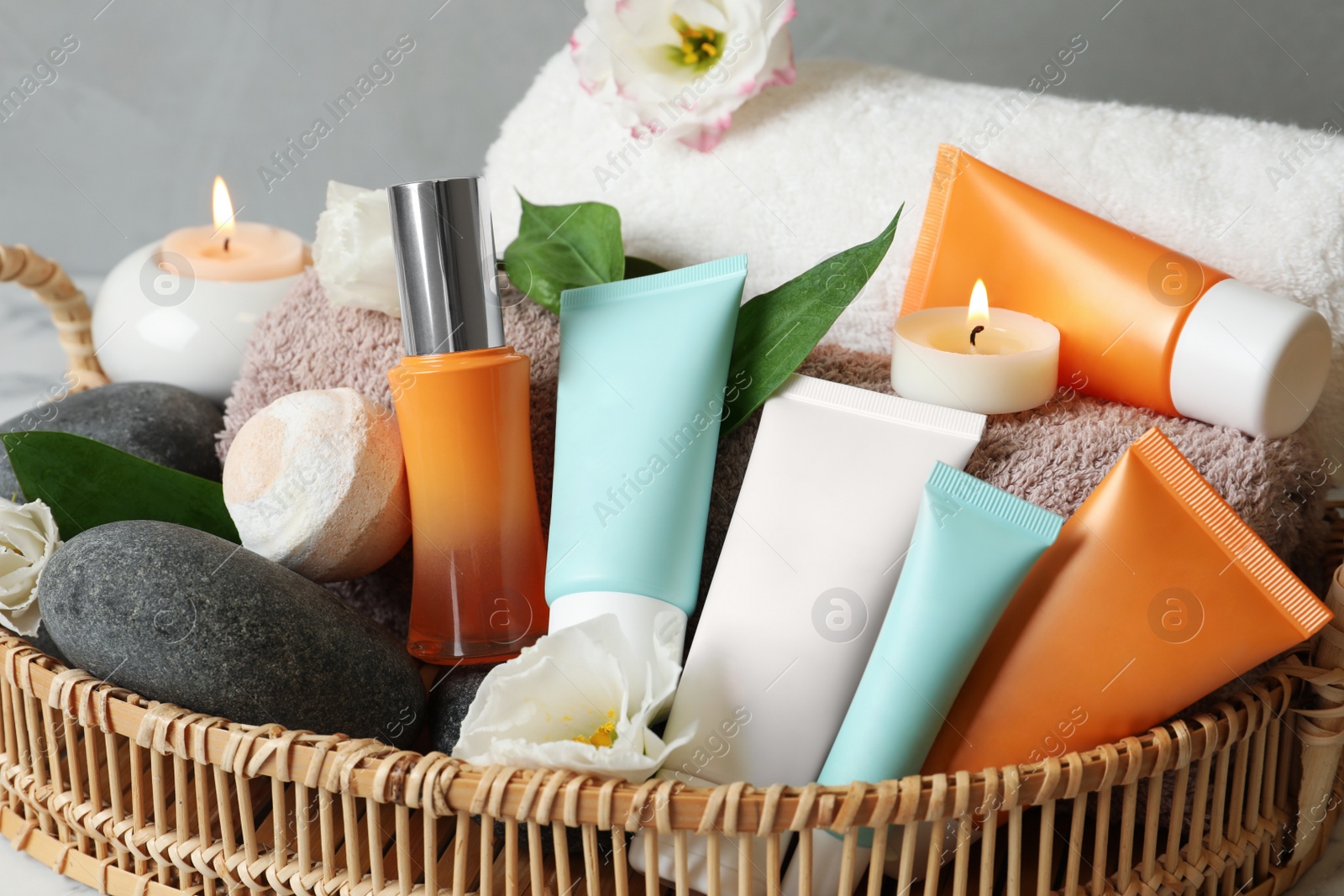 Photo of Cosmetic products and towels in wicker tray, closeup