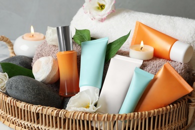 Photo of Cosmetic products and towels in wicker tray, closeup
