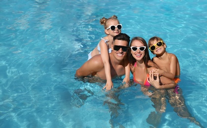 Photo of Happy family in outdoor swimming pool on sunny summer day. Space for text