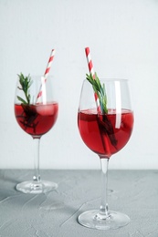 Photo of Tasty refreshing cranberry cocktail with rosemary on table