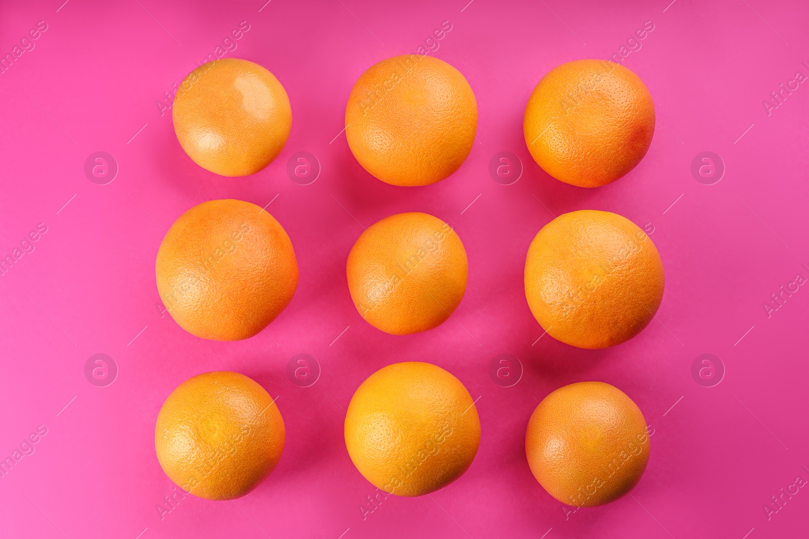 Photo of Tasty ripe grapefruits on magenta background, flat lay