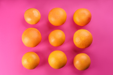 Tasty ripe grapefruits on magenta background, flat lay