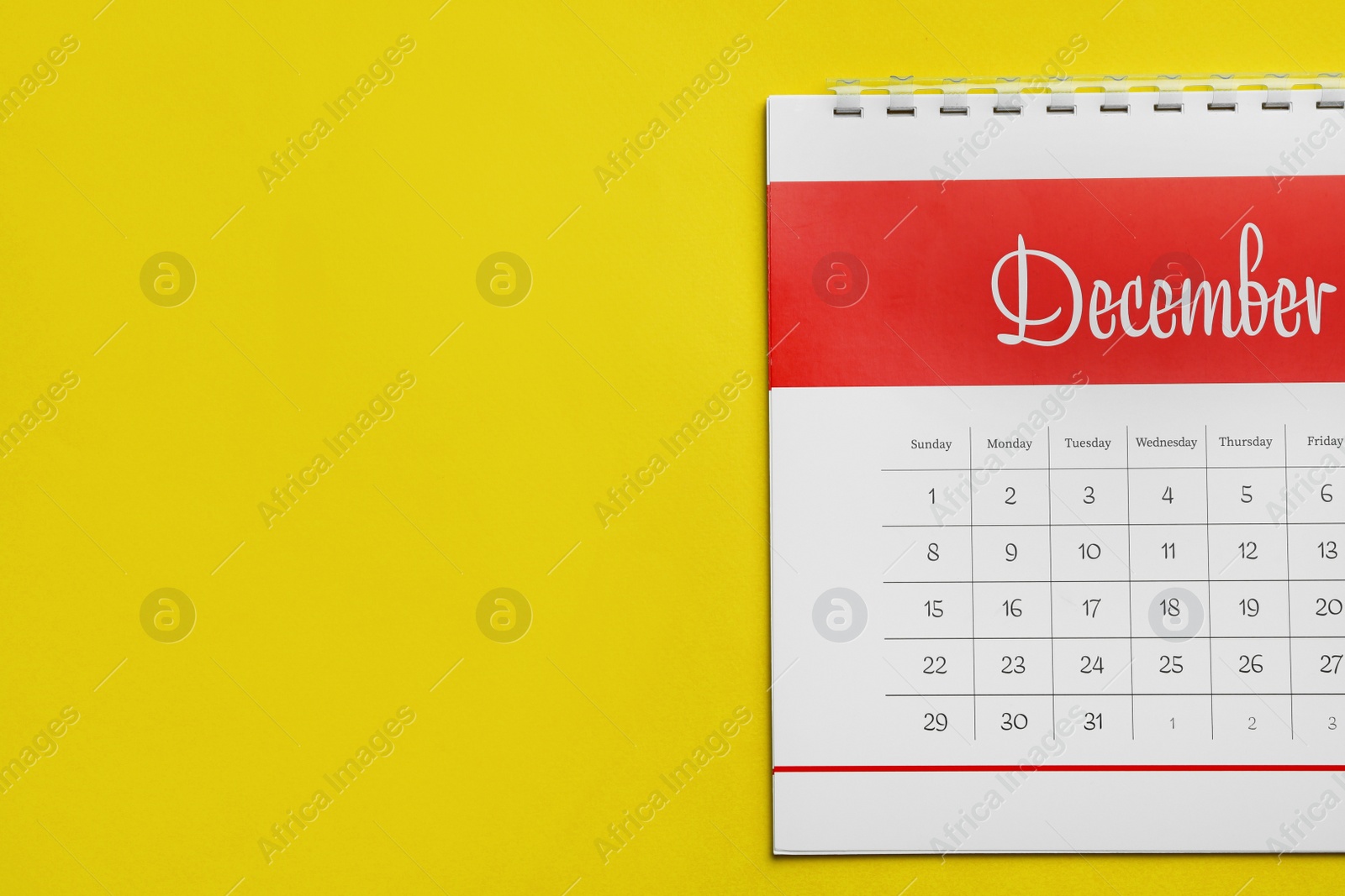 Photo of December calendar on yellow background, top view. Space for text