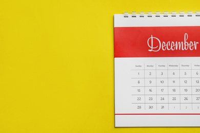 Photo of December calendar on yellow background, top view. Space for text