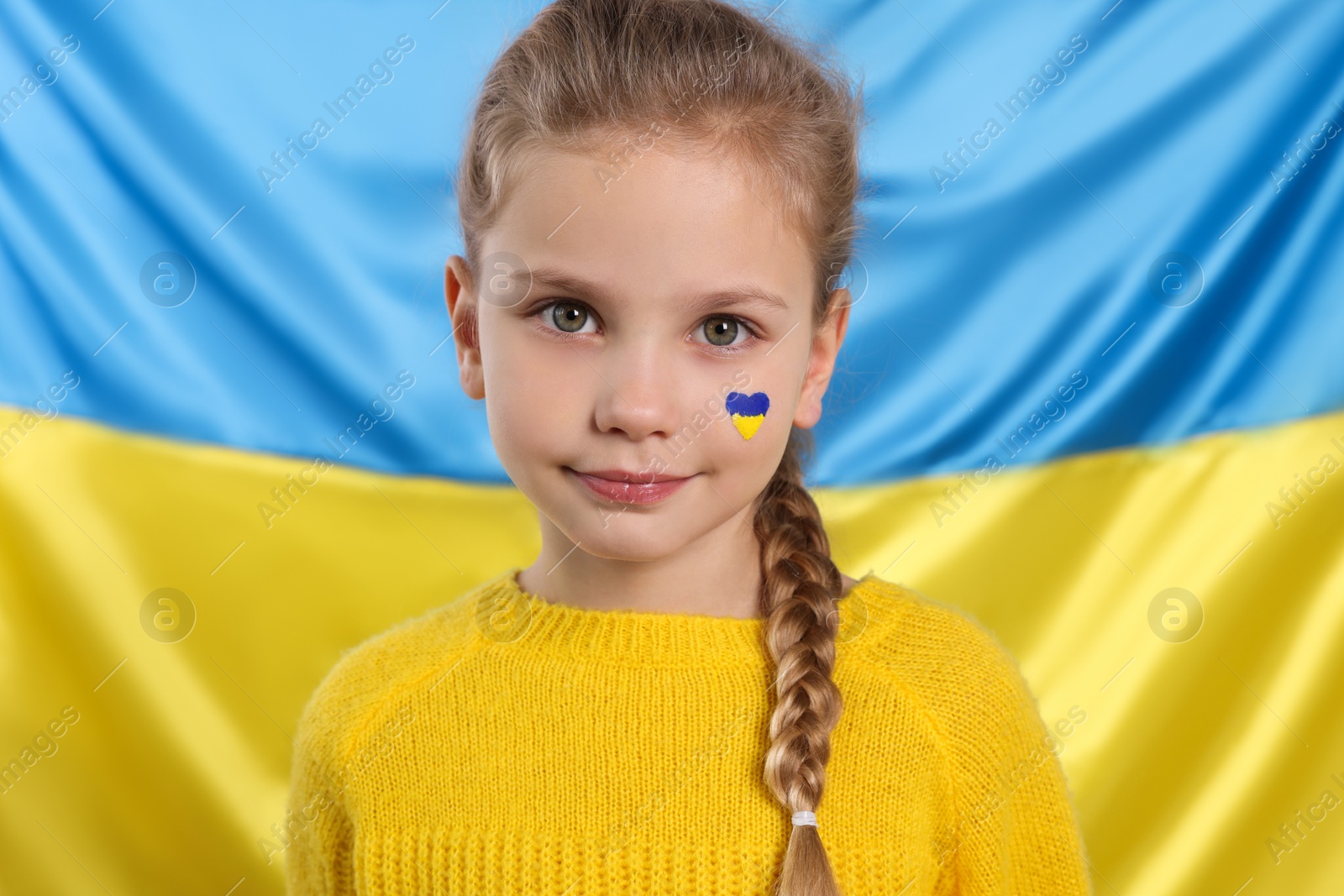 Photo of Little girl with face paint near Ukrainian flag