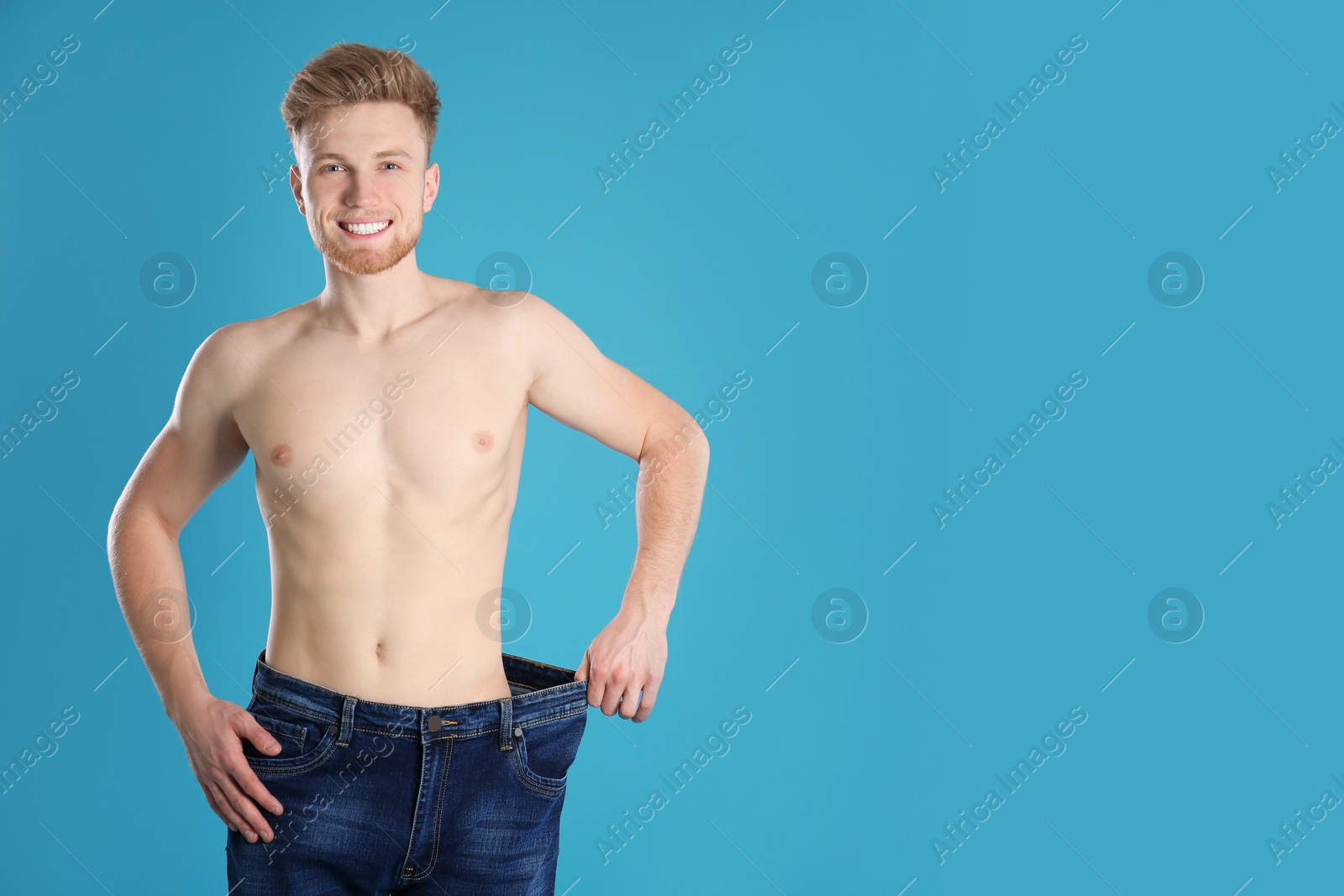 Photo of Handsome man in oversized jeans on color background. Space for text