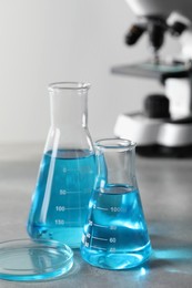 Photo of Different laboratory glassware with light blue liquid on table