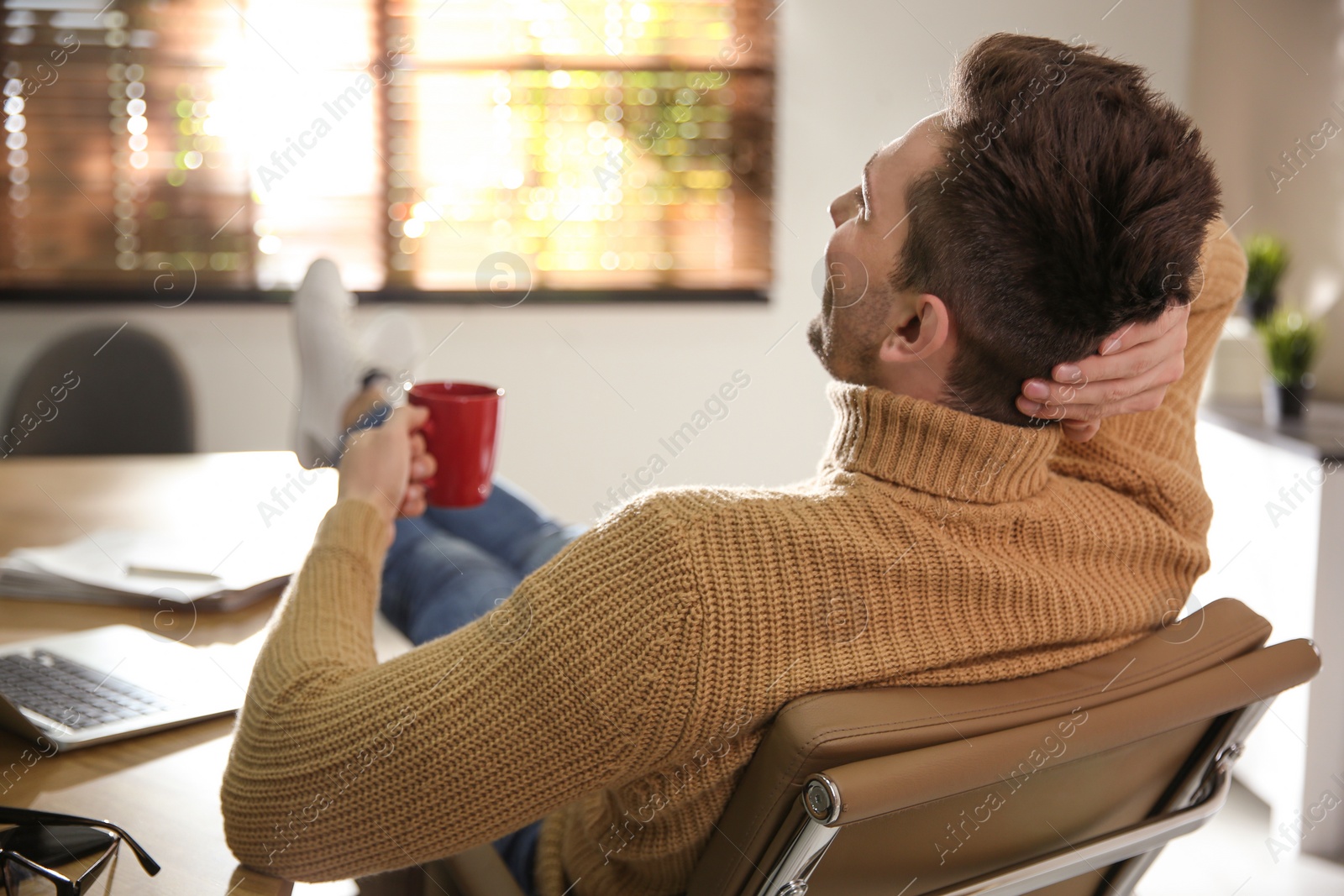 Photo of Young man with cup of drink relaxing at workplace