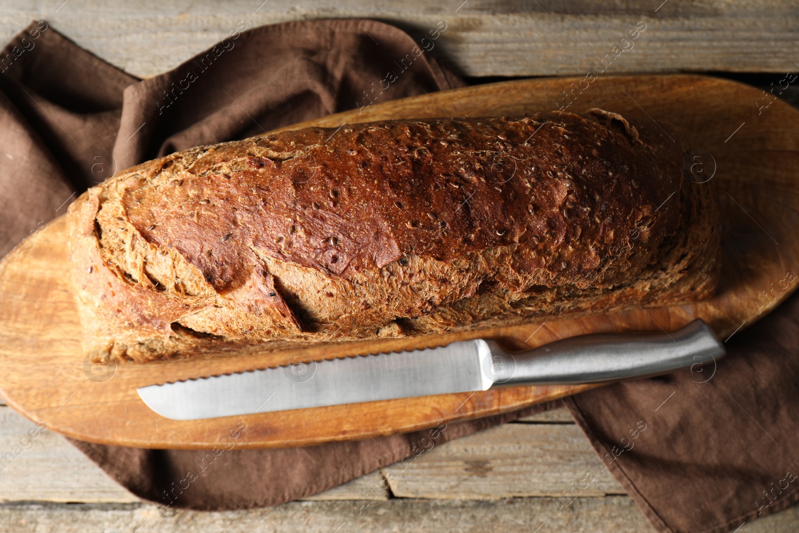 Photo of Freshly baked sourdough bread and knife on wooden table, top view