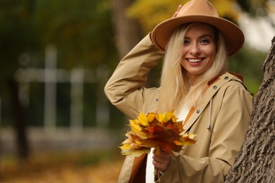 Photo of Happy woman with autumn leaves outdoors. Space for text
