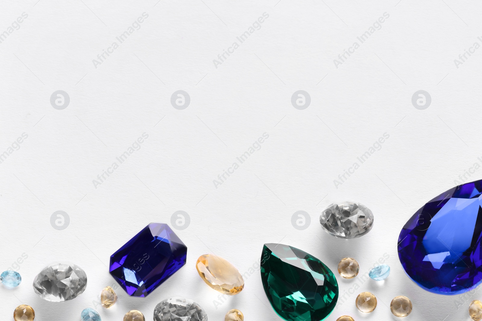 Photo of Different beautiful gemstones for jewelry on white background, top view. Space for text