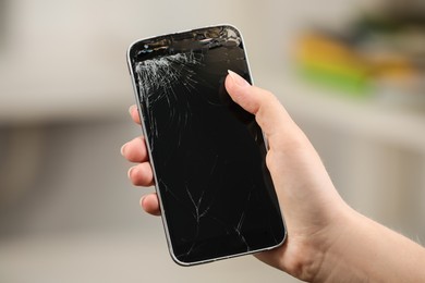 Photo of Woman holding damaged smartphone on blurred background, closeup. Device repairing