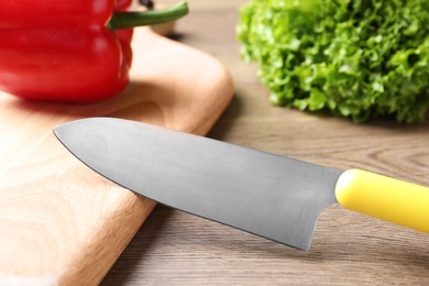 Photo of Cutting board and sharp chef's knife on wooden table